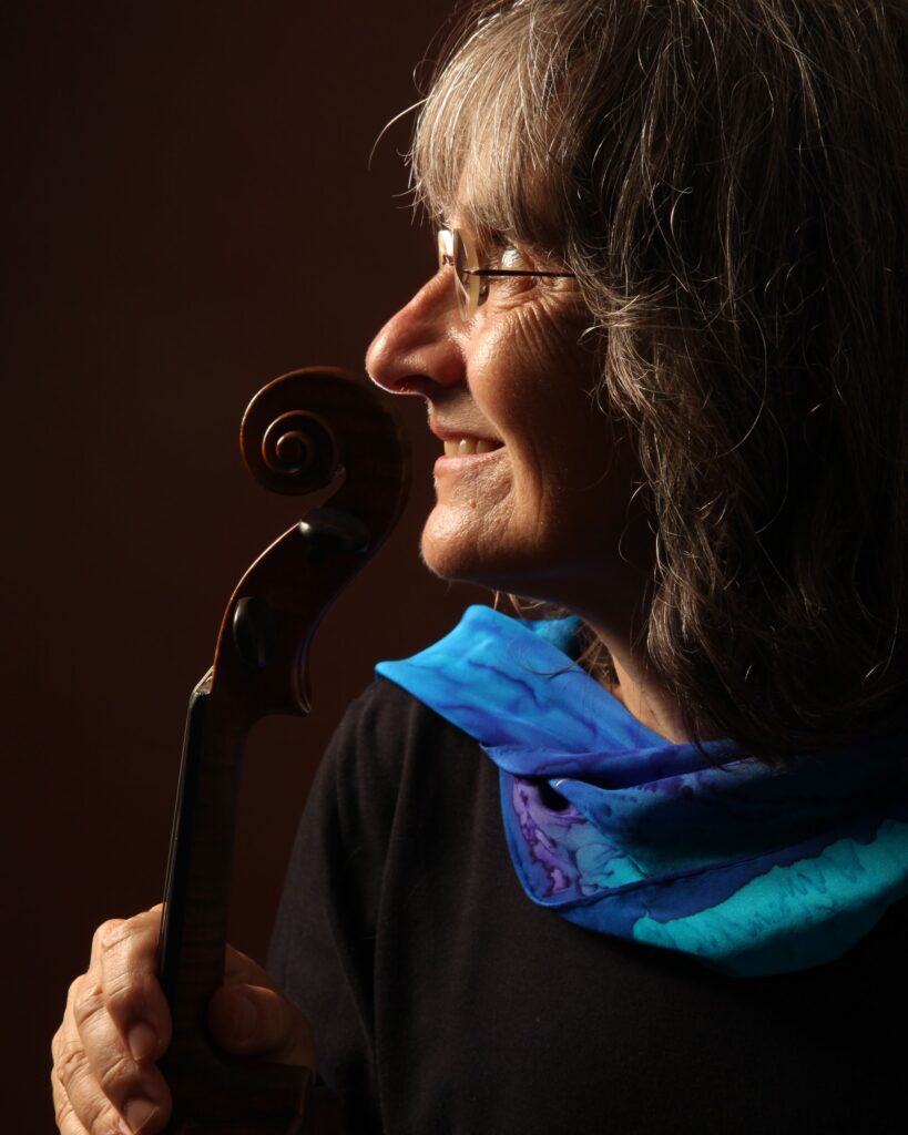Andrea Hoag in blue scarf in profile with fiddle scroll
